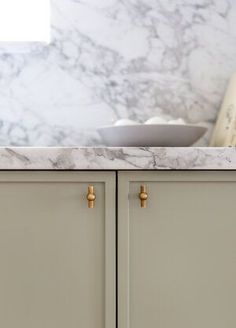 a marble counter top in a kitchen with gold handles and knobs on the cabinet doors