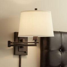 a lamp is on the wall next to a black leather bed headboard and night stand