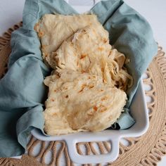 some kind of food in a white bowl on a doily with a blue cloth