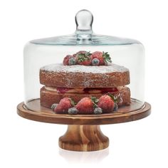 a cake under a glass dome with strawberries on top and powdered sugar on the bottom