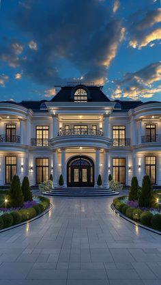 a large white mansion with lots of windows and lights on it's front entrance