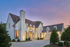 a large white house with lots of windows and lights on it's roof is lit up at night