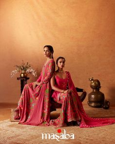 two women in pink dresses sitting on a chair