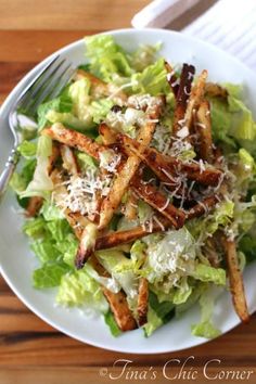 a salad with french fries and parmesan cheese on top is ready to be eaten