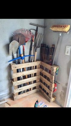 a wooden crate filled with gardening tools on top of a floor next to a wall