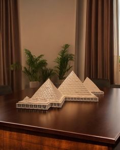 two model pyramids sitting on top of a wooden table in front of a window