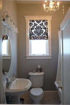 a white toilet sitting under a window next to a sink and bathtub in a bathroom