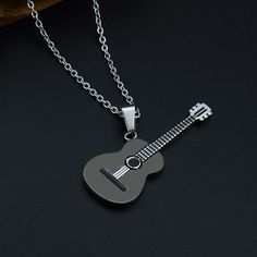 a guitar shaped pendant is shown on a black surface, with a chain attached to it