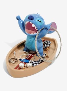 a toy elephant with its mouth open and some jewelry in it's hand on a tray