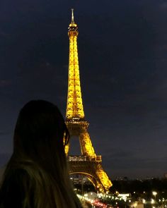 a woman standing in front of the eiffel tower at night