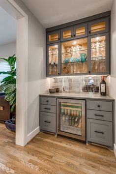 a kitchen with gray cabinets and wood flooring in the middle of it is lit by recessed lighting