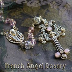 "This rosary is based on old French rosaries I used to see in the in the stalls of Parisian flea markets with Marian centerpiece and Angel cross.  The angel is flanked by bezel and prong settings which hold crystal and vintage glass cabochons The five decades are 8mm premium faceted crystal beads. The mysteries are 10mm crystal beads. The five decades are 32\" (81 cm) long and 5\" (13 cm) more to the cross. Blue and pink have burnished silver finish. Red & Green has a burnished bronze finish. Ni Antique Jewelry With 8mm Beads As Gift, Antique Jewelry With 8mm Beads For Gift, Antique 8mm Beads Jewelry As Gift, Vintage Beaded Rosary As Gift, Antique Crucifix Rosary As Gift, Antique Crucifix Rosary Gift, Antique Silver Rosary For Gift, Vintage Rosary With Round Beads As Gift, Vintage Rosary Bracelet With Round Beads As Gift