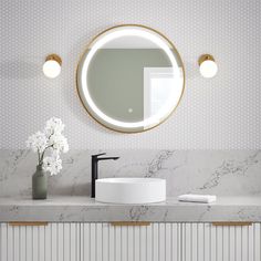 a bathroom with marble counter top and round mirror