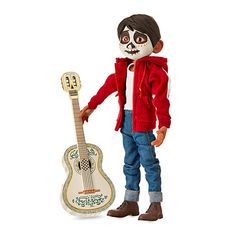 a doll is holding a guitar and wearing a red jacket with a skull on it