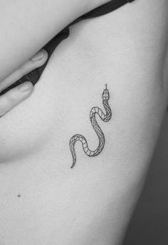 a black and white photo of a woman's stomach with a snake tattoo on it