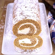 there is a roll that has been cut in half on a white plate with powdered sugar