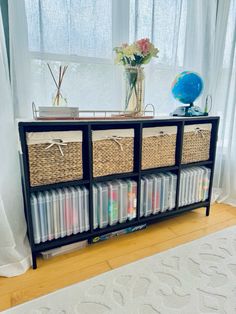 a black shelf with baskets on top of it next to a white rug and window