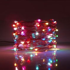 multi - colored christmas lights are arranged on a table in front of a dark background