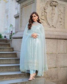 a woman in a blue dress standing on some steps