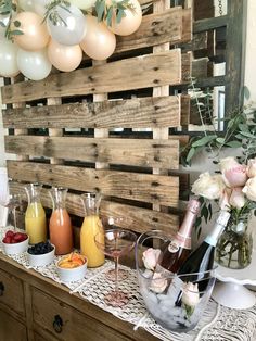 a table topped with bottles of wine and glasses filled with drinks next to balloons in the air