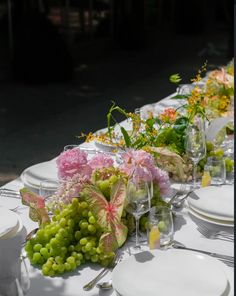 a long table is set with white plates and flowers