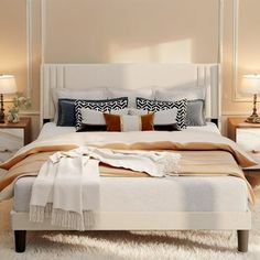 a white bed with pillows and blankets on top of it next to two nightstands