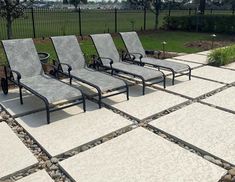 four lounge chairs sitting on top of a stone patio