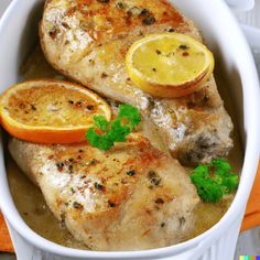 two pieces of chicken with lemons and parsley in a white bowl