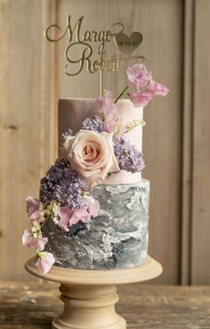 a multi - tiered cake with pink and purple flowers on top