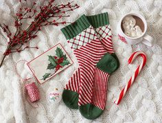 a knitted christmas stocking with candy canes, marshmallows and other holiday items