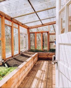 the inside of a greenhouse with lots of plants growing in it and windows on both sides