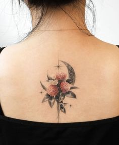 a woman's back tattoo with flowers and a crescent moon on her left shoulder