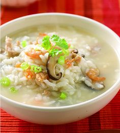 a white bowl filled with rice and vegetables on top of a red table cloth next to a fork