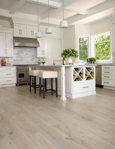 a large kitchen with white cabinets and wooden floors