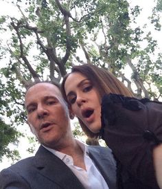 a man and woman taking a selfie with trees in the background