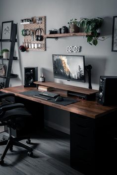 a desk with a computer and speakers on it in front of a wall mounted clock