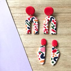 three pairs of colorful earrings on a table