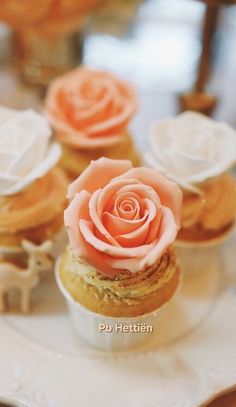 some cupcakes with frosting and roses on them are sitting on a plate