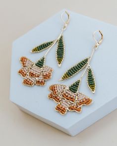 a pair of earrings with beaded leaves hanging from it's earwires