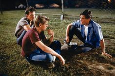 three young men sitting on the ground talking