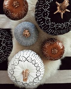 four decorative pumpkins sitting on a black and white striped rug with gold star decorations