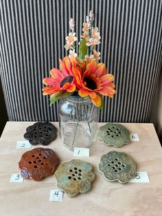 a vase filled with flowers sitting on top of a wooden table next to buttons and numbers