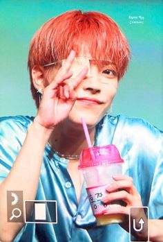 a person with red hair holding a drink in front of their face and looking at the camera