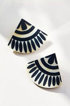 two black and white earrings on a white surface, one with an eyeball design