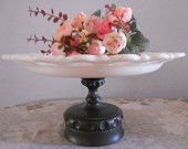 a cake plate with flowers on it sitting on a table