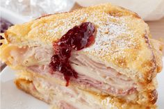 a cut in half ham and cheese sandwich on a white plate with powdered sugar