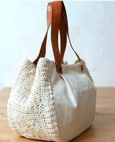 a crocheted white purse sitting on top of a wooden table next to a wall