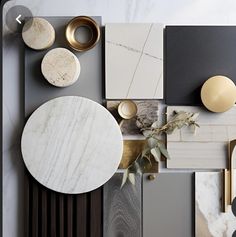 an assortment of marble and metal items on display in a room with white walls, black flooring and gold accents