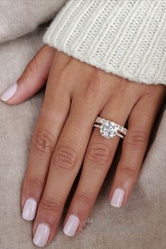 a woman's hand with a ring on it and a white sweater behind her