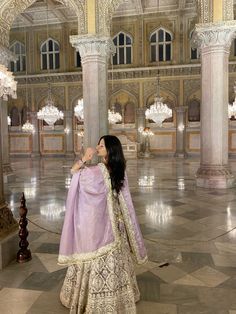 a woman in a purple and white dress standing inside an ornate building